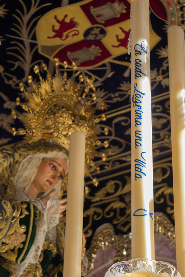 la virgen en el palio con cirio en primer plano